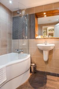 
a white bath tub sitting next to a white sink at Thornton Hall Hotel & Spa in Heswall
