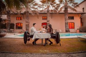 a man and woman sitting at a table in front of a house at Apartamento el Benicadell in Adzaneta de Albaida