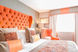 a bedroom with a large bed with an orange headboard at Thornton Hall Hotel & Spa in Heswall