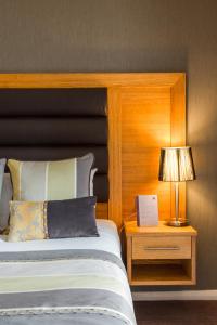 a bedroom with a bed and a lamp on a night stand at Thornton Hall Hotel & Spa in Heswall
