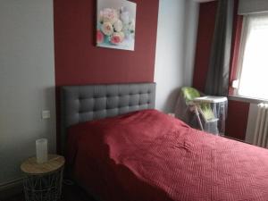 ein Schlafzimmer mit einem Bett mit einer roten Wand in der Unterkunft NIBENAMA in Gérardmer