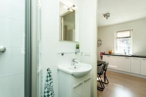 a white bathroom with a sink and a mirror at Stayci Serviced Apartments Central Station in The Hague +74 photos