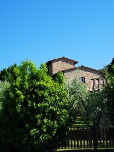 an old stone building behind some trees and a fence at Frateria Di San Benedetto in Montepulciano