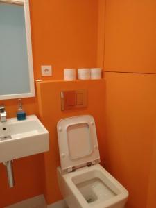 baño de color naranja con aseo y lavamanos en Prague Saints Apartments, en Praga
