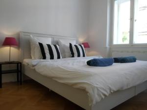 Cama blanca con almohadas blancas y negras y ventana en Prague Saints Apartments, en Praga