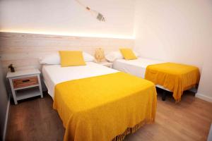 two beds in a room with yellow sheets at Apartamento frente al mar in Canet de Mar