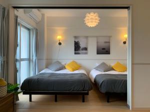 two beds in a room with a mirror at Allstay CHIBANA in Okinawa City