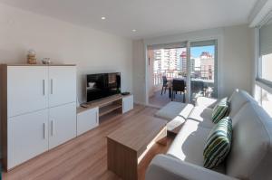 a living room with a white couch and a tv at Torres Del Mar in Playa de Gandia