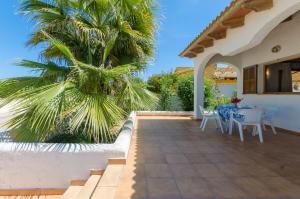 a patio with a palm tree and a table and chairs at Perú in Son Serra de Marina