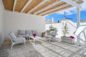 een patio met stoelen en een tafel op een witte muur bij CasaMia in Alliste