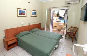 um quarto com uma cama verde e uma varanda em Katerina Hotel em Agia Marina