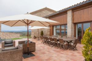 a patio with a table and chairs and an umbrella at El Porxo de Mateus in Sagás