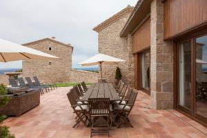 a wooden table with chairs and umbrellas on a patio at El Porxo de Mateus in Sagás