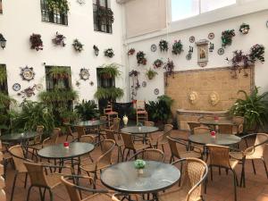 una habitación con mesas, sillas y plantas en Hotel de Los Faroles, en Córdoba