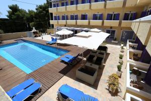 uma piscina com cadeiras e guarda-sóis ao lado de um edifício em Katerina Hotel em Agia Marina