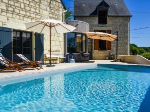 a swimming pool with two chairs and an umbrella at Holiday home near Thizay with private pool in Thizay