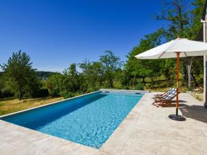 ein Pool mit einem Sonnenschirm, zwei Gartenstühlen und einem Sonnenschirm in der Unterkunft Holiday home near Thizay with private pool in Thizay