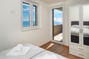 a bedroom with a bed and a balcony with the ocean at Panorama lux apartment in Rogoznica
