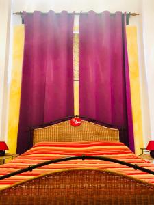 ペスカンティーナにあるB&B A Casa di Saraのベッドルームに紫色のカーテン付きのベッド1台