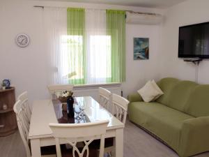 uma sala de estar com uma mesa e um sofá verde em Charming Apartment in Greba tica with Terrace em Grebaštica