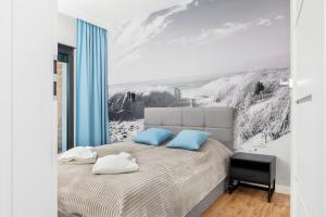 sypialnia z dużym łóżkiem i niebieskimi poduszkami w obiekcie Apartamenty Gardenia Seaside by Noclegi Renters w Dziwnowie