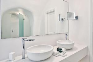 a bathroom with two sinks and a large mirror at Canaves Oia Suites & Spa in Oia