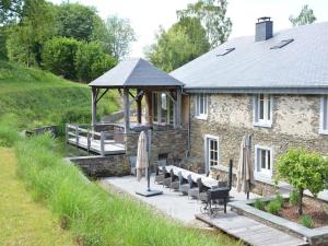 a stone house with a gazebo and benches in front of it at Authentic Holiday Home located in Bievre with Jacuzzi in Bièvre
