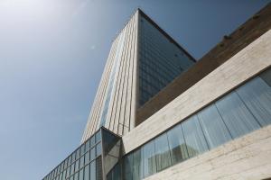 a tall glass building with a blue sky in the background at Holiday Inn - Tbilisi, an IHG Hotel in Tbilisi City
