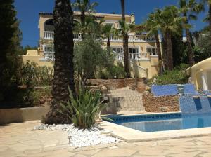 a house with a palm tree and a swimming pool at Casa Grecia in Santa Eularia des Riu