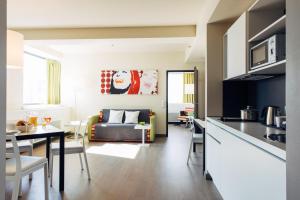 harry's home hotel & apartments في فيينا: مطبخ وغرفة معيشة مع طاولة وأريكة