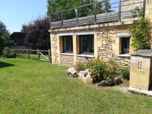 a stone house with a balcony on top of a yard at Les Buis in Castelnaud La Chapelle