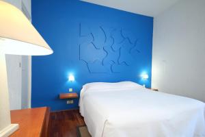 a blue bedroom with a white bed and a blue wall at Le Windsor, Jungle Art Hotel in Nice