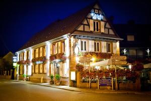 a building with signs in front of it at night at Logis Hotel Aux Comtes De Hanau in Ingwiller