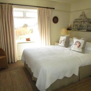 a bed room with a white bedspread and a white comforter at Driftwood in Porthscatho