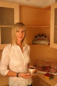 a woman standing in a kitchen holding a plate of food at Pension Schöpf in Arzl im Pitztal