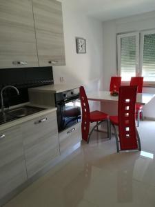 a kitchen with red chairs and a table with a sink at Apartman Tonika in Pula