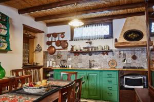 una cocina con armarios verdes y una mesa con un bol de fruta en La casa del Balivo, en Dorgali