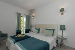 a hotel room with two beds and a window at Rocha Brava Village Resort in Carvoeiro