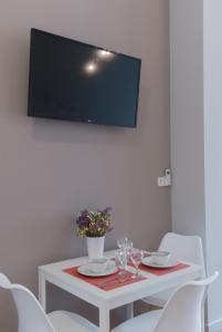 a white table with chairs and a television on a wall at Saint George unique studio in Nafplio