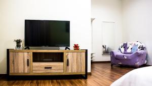 sala de estar con TV y silla morada en TROPICAL LIVINGS MERU IPOH HOMESTAY by Grab A Stay en Ipoh