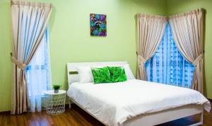 a bedroom with a white bed and two windows at TROPICAL LIVINGS MERU IPOH HOMESTAY by Grab A Stay in Ipoh