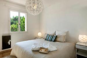 a bedroom with a bed with two pillows and a chandelier at Villa provençale avec piscine-56 in La Garonnette-Plage