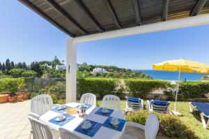 a table with chairs and an umbrella on a patio at Rocha Brava Village Resort in Carvoeiro