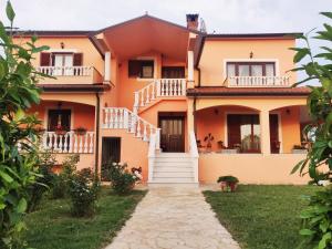 een oranje huis met witte balkons en een pad bij Apartment Luna in Umag