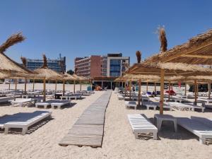 a beach with chairs and straw umbrellas and benches at Mamaia Beach Side in Mamaia