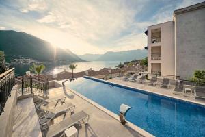 einen Hotelpool mit Blick auf das Wasser in der Unterkunft HUMA Kotor Bay Hotel and Villas in Kotor