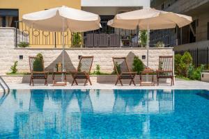 a pool with two chairs and two umbrellas and a table and chairsearch at Sealine Apartments A2 in Tivat
