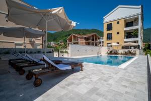a pool with two lounge chairs and an umbrella next to a building at Sealine Apartments A2 in Tivat