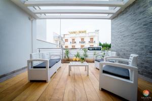 un balcone con sedie bianche, tavolo e un edificio di Perle Del Mare - Appartamenti di Pregio 70m spiaggia Pescoluse a Marina di Pescoluse