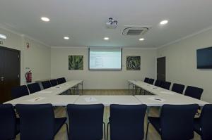 a conference room with tables and chairs and a screen at Rocha Brava Village Resort in Carvoeiro